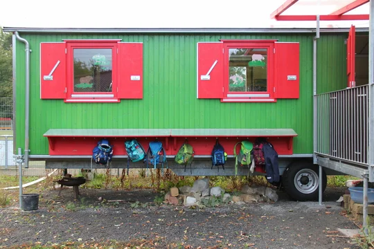 Ein Bild vom Naturkindergarten mit den Rucksäcken von Kindern die an der Wand aufgehangen sind